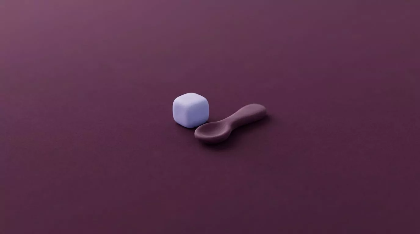 A clay sugar cube beside a teaspoon, illustrating how many calories in a gram of sugar